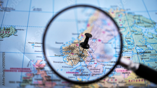 Photography Close-up of a printed map with a magnifying glass highlighting Oslo