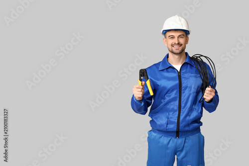 Принти на полотні Portrait of male electrician with wires and crimper on grey background