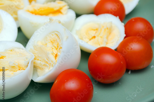 Halved Hard-Boiled Eggs and Fresh Cherry Tomatoes on a Green Plate