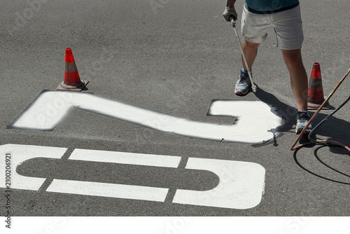 Road worker painting speed limit 20 marking on asphalt street
