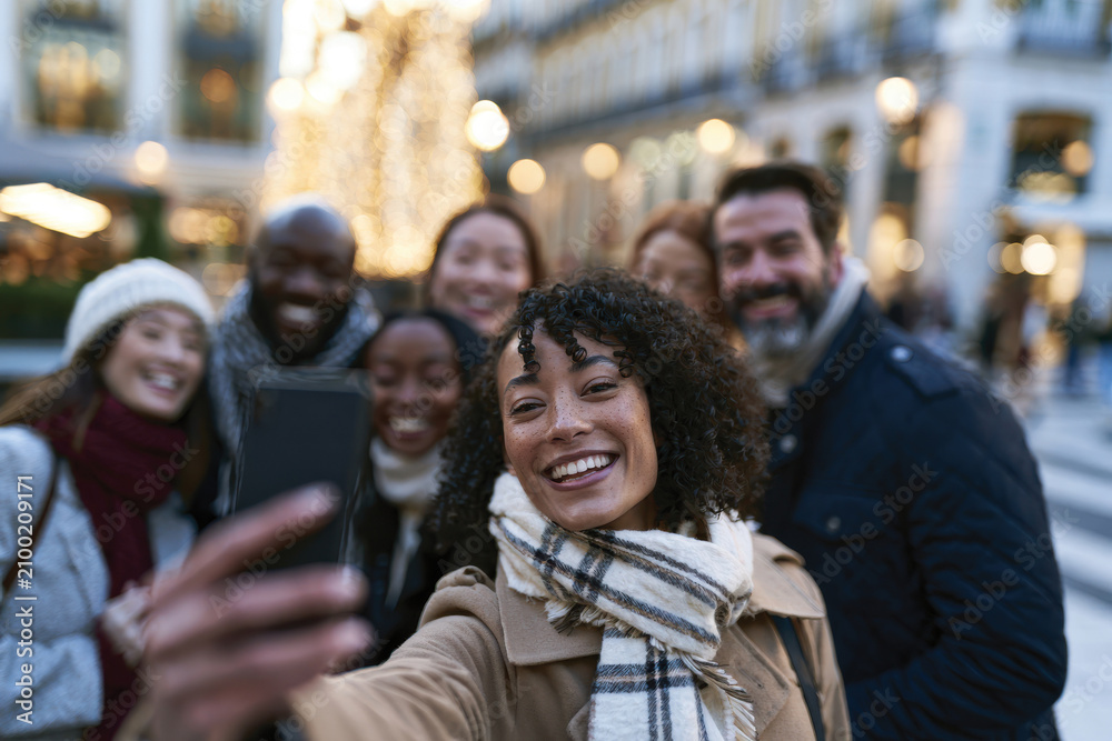 Obraz premium A joyful group of friends captures a selfie in an outdoor setting adorned with festive lights, conveying a sense of camaraderie, joy, and shared memories.