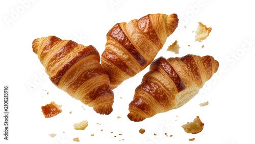 Isolated three fresh flaky golden croissants with delicious crumbs flying in the air