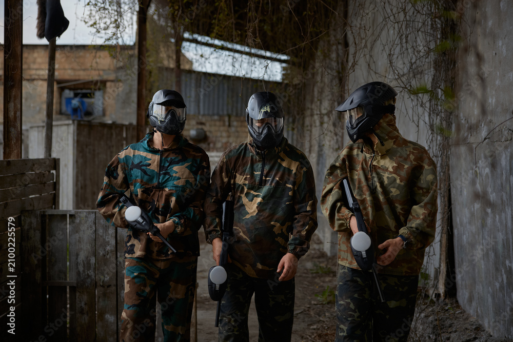 Fototapeta premium An armed group of three people practice with weapons on a training field outdoor