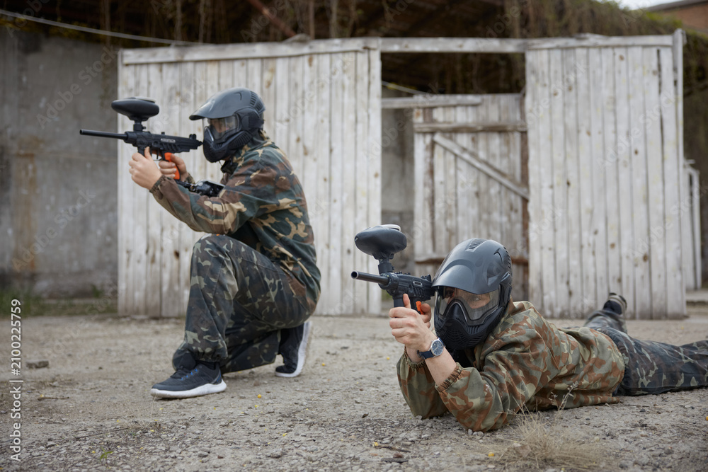 Fototapeta premium Soldiers are taking positions during tactical weapon training, one aims while sitting on the ground