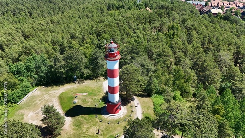 Cuadro en lienzo Aerial high angle view of Nida lighthouse with a long shadow in a green pine forest on Curonian Spit, Lithuania