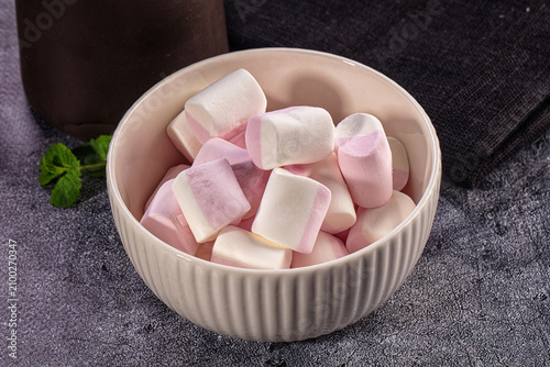 Pink and white marshmallows in ceramic bowl with mint leaf