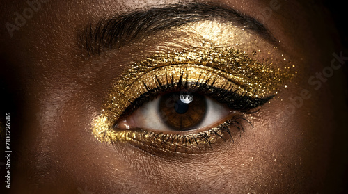 Macro shot of a brown eye with luxury gold glitter eyeshadow