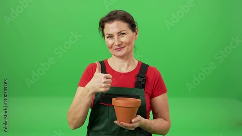 Smiling Woman Gardener Giving Thumbs Up Holding Terracotta Pot Against Green Screen Background