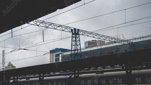 Foto Industrial overhead power lines and steel gantries above railway tracks at a train station under an overcast sky