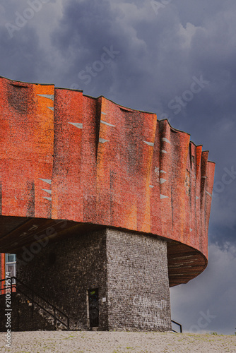Monumental Brutalist architecture with vibrant mosaic facade against dramatic sky