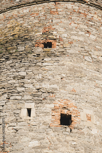 Ancient stone tower wall with small openings and weathered brick details