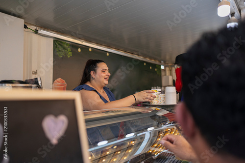 Woman vendor smiling serving customer in food truck