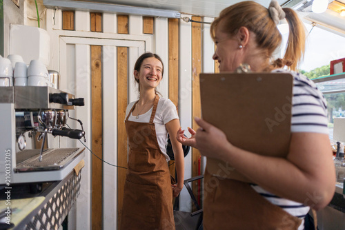 Coffee shop owner supervising young trainee barista learning work