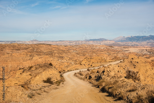 Dirt road leads into the eroded badlands of the Gorafe Desert in northeastern Granada, Spain