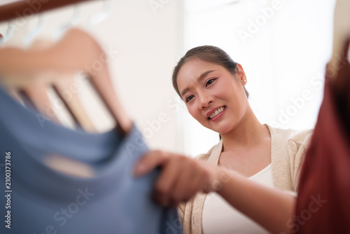 Foto Smiling woman chooses clothing from a home wardrobe, highlighting organized storage, garment care, and a tidy modern lifestyle with practical home management