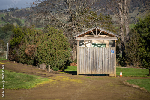 A public toilet block with a wooden privacy fence in a rural Australian park setting
