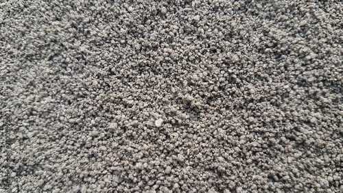 A close-up texture of coarse gray construction sand with natural grain detail.