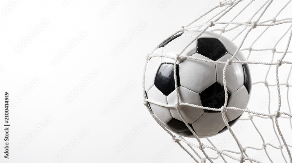 Fototapeta premium Classic black and white soccer ball with a victorious mood scoring a goal against a white net backdrop with copy space