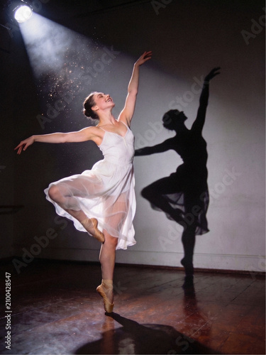Dancing shadow, A photographic ballerina in a white dress in the bright light of spotlights and in the shadows , stock photo