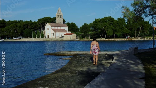 Woman admiring coastal church across calm bay