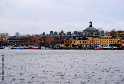 distant view of the Skeppsholmen island waterfront across the Ladugårdslandsviken waterway under an overcast sky in Stockholm, Sweden