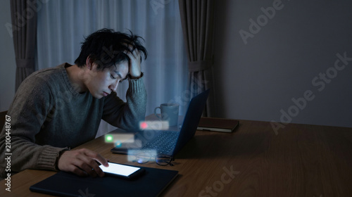 Worker up late with tablet and laptop displaying floating digital UI