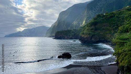 Beautiful view of Seixal Beach with black volcanic sand, Atlantic Ocean and green mountains on Madeira Island, Portugal.
