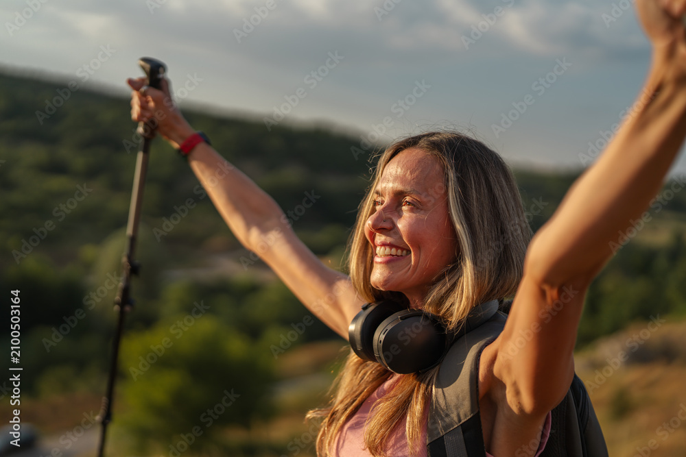 Obraz premium Woman hiker celebrating success raising arms on mountain