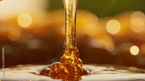 Close-up of Golden Honey Dripping with Bokeh Background.