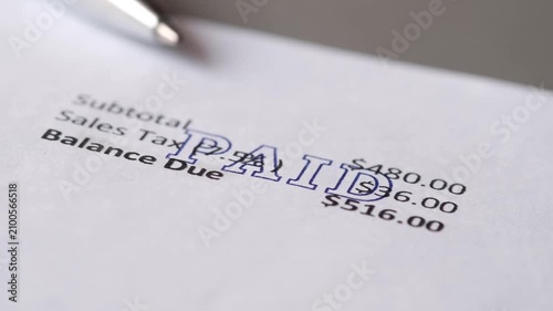 Paid stamp being applied to financial document with subtotal sales tax and balance due