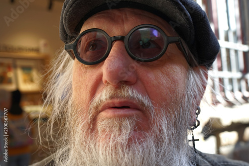 Принти на полотні An senior man is shown with a beard, wearing round black glasses and a dark cap