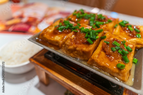 Pan fried tofu served with sauce on a plate with garnishments in a traditional setting on Hong Kong Island