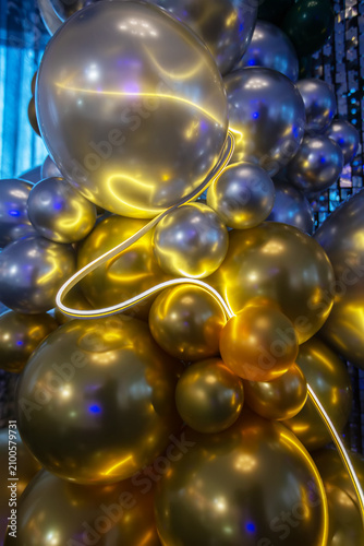 Shimmering gold and silver balloon display with ambient lighting and colorful reflections for celebratory mood