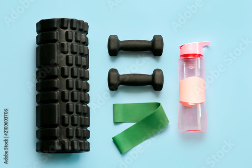 Top view of muscle massage roller,black dumbbells,elastic resistance band and water bottle. Sport and fitness concept