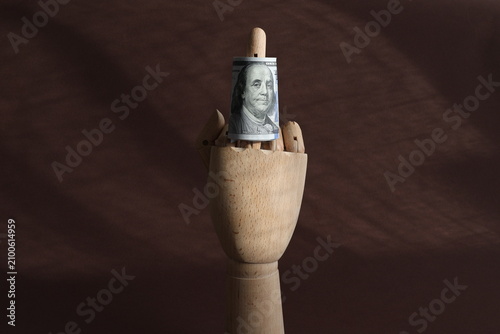 Obraz na płótnie Conceptual Satire: Wooden Mannequin Hand Showing Middle Finger with a Dollar Bil