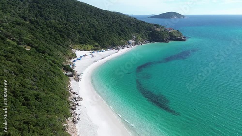 Cinematic aerial footage revealing the spectacular coastline of Pontal do Atalaia in Arraial do Cabo, Rio de Janeiro, Brazil. Crystal-clear turquoise waters, lush green hills.