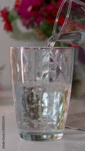 Close up of fresh pure water pouring into glass on table vertical