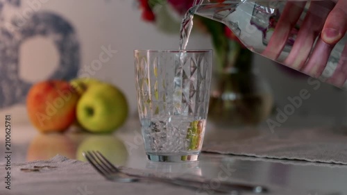 Pouring fresh pure water into transparent glass before dinner