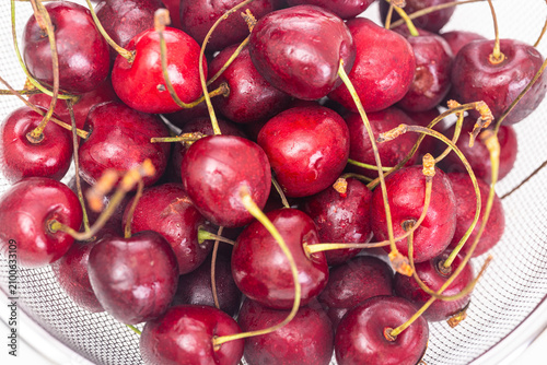 Ripe cherries in a colander close up on a white background