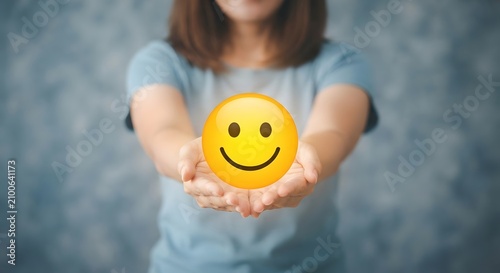 Woman holding smiley face. Female offering happy emoticon.