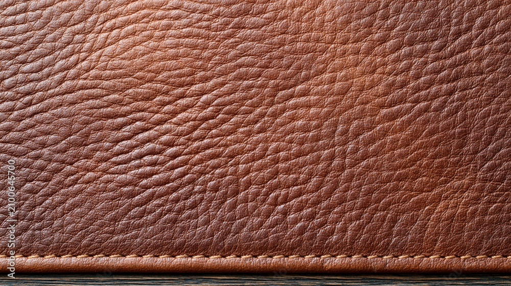 Fototapeta premium Close-up detailed texture of rich brown genuine leather with visible grain and stitching, elegant material background