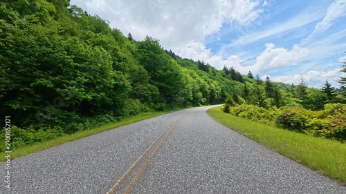 Driver’s perspective on the road leading to Waterrock Knob in North Carolina, with lush green mountains rising on the left and forest-covered ridgelines stretching along the right