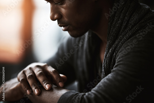 Man in deep thought, head bowed, hands clasped in contemplation