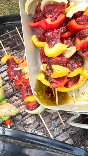 Grilling skewers on a charcoal BBQ, glazed with sauce while cooking.