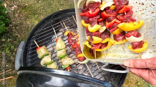 Grilling skewers on a charcoal BBQ, glazed with sauce while cooking.