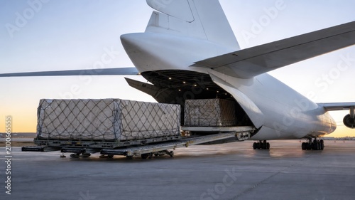 Cargo is loaded into a large aircraft at an airport during early morning hours