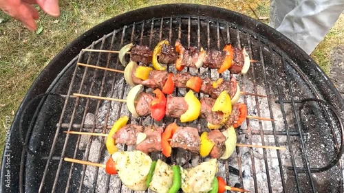 Carefully turning meat and fish skewers as they grill over charcoal.