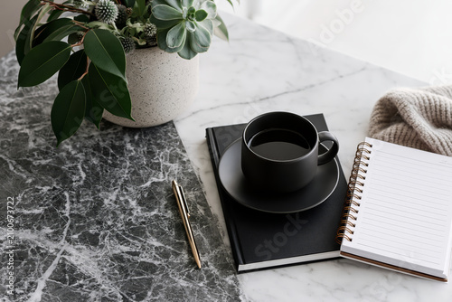Minimalist desk setup with coffee, notebook, and plant on marble surfaces