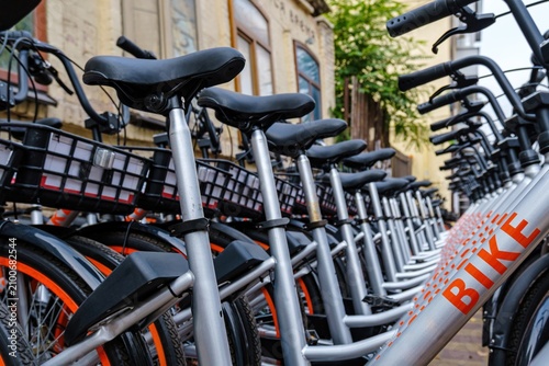 Row of modern rental bicycles parked on a city street. Close view highlights bike sharing, sustainable transportation, urban mobility and eco friendly travel