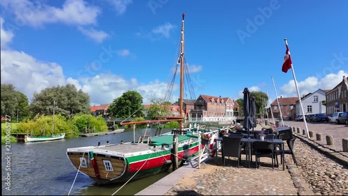 Ribe, Denmark – Historic waterfront promenade with sailing boat, a restaurant terrace and a summer harbor atmosphere